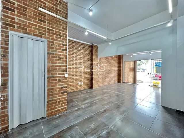 Interior de um espaço amplo com paredes de tijolo aparente e piso de concreto.