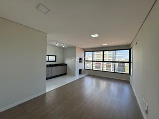 Sala de estar ampla com piso de madeira e vista da cidade.