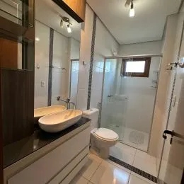 Foto de um banheiro com box de vidro e revestimento branco.