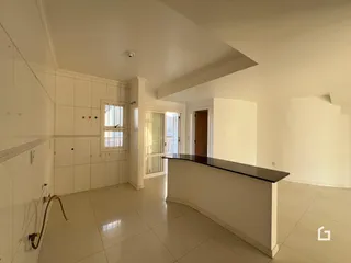 Interior de uma sala com piso de cerâmica clara e paredes brancas.