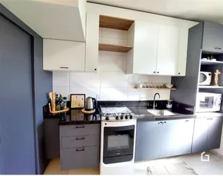 Cozinha moderna com armários brancos e bancadas escuras.