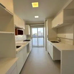 Corredor interno com armários brancos e piso claro em um imóvel.