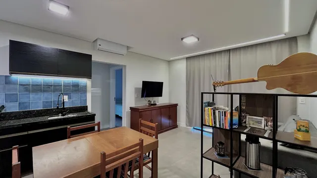 Ambiente interno com mesa de jantar de madeira e estante decorativa em um apartamento.