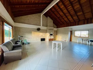 Sala de estar ampla com piso de cerâmica e teto de madeira em uma residência.