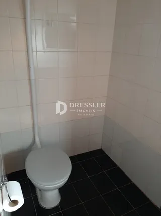 Foto de um vaso sanitário em um banheiro com azulejos brancos.