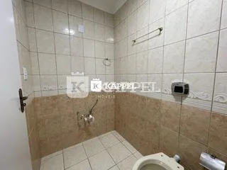 Banheiro com revestimento de azulejos claros nas paredes e piso.