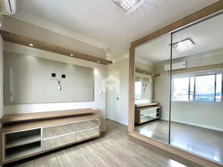 Ambiente interno de uma sala com piso de madeira e espelho grande.