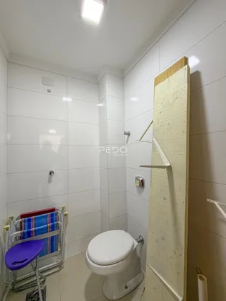 Foto de um banheiro com revestimento cerâmico branco.