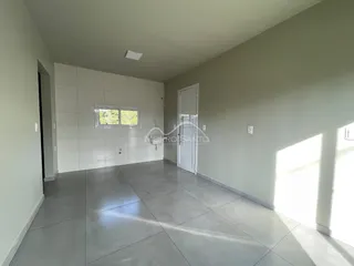 Vista interna de um ambiente amplo com piso de concreto e paredes brancas.
