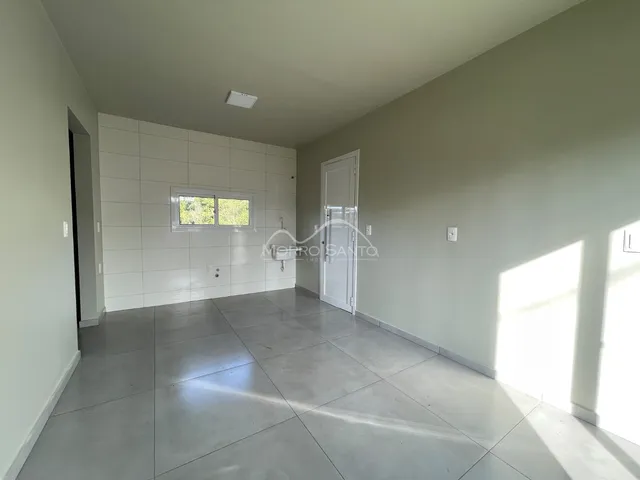 Vista interna de um ambiente amplo com piso de concreto e paredes brancas.