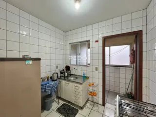 Interior de um cômodo com revestimento de azulejos brancos e uma bancada.