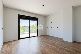 Sala de estar com piso de madeira e porta de vidro voltada para a paisagem.