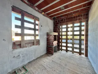 Vista interna de um ambiente com paredes de tijolo aparente e teto de madeira.