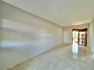 Ambiente interno de uma sala com piso de cerâmica clara e paredes brancas.
