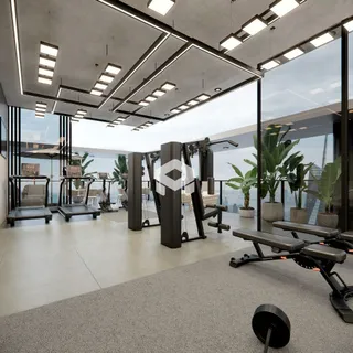 Espaço comum com equipamentos de ginástica e grandes janelas.