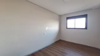 A foto mostra uma sala de estar com paredes brancas e piso de madeira.