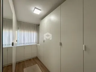 Vista interna de um corredor com armários embutidos e piso de madeira.