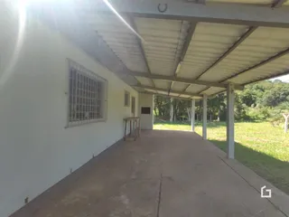 Vista externa de uma área coberta com parede branca e telhado de zinco.