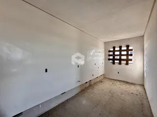 Interior de um cômodo com paredes brancas e piso de concreto.