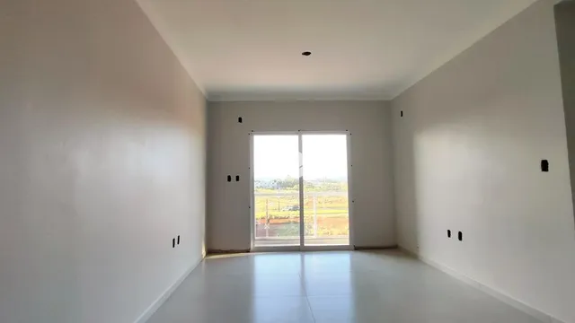 Uma sala de estar vazia com paredes brancas e uma grande janela.