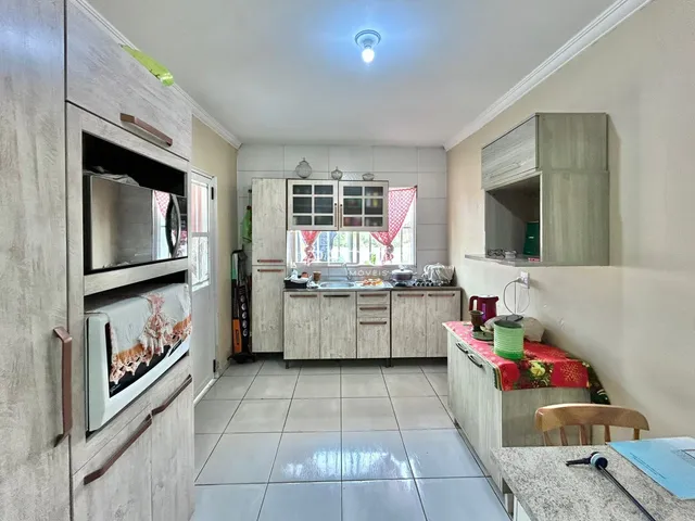 Imagem de uma cozinha com armários e piso de cerâmica em um imóvel no Brasil.