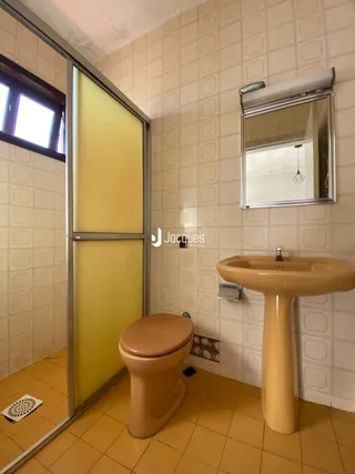 Foto de um banheiro com azulejos claros e pia de pedestal.