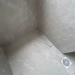Vista de um canto de parede com piso claro em um imóvel.