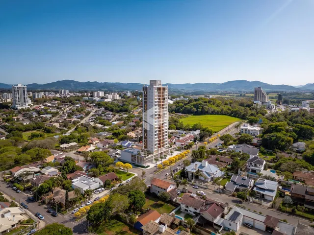 Vista aérea de um bairro residencial em Lajeado, Brasil, mostrando edifícios e áreas verdes.