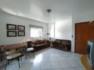 Uma sala de estar com sofá marrom e piso de cerâmica clara.