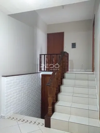 Vista de um corredor com escadaria e parede de tijolos brancos.