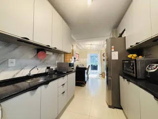 Vista da cozinha com armários brancos e bancadas escuras.