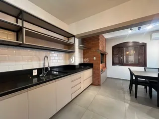 Foto de uma cozinha moderna com armários brancos e bancadas escuras.