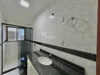 Banheiro com revestimento de azulejos brancos e bancada escura.