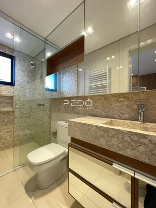 Foto de um banheiro com revestimento de azulejo e box de vidro.