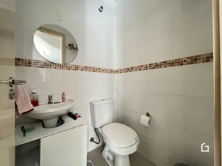 Banheiro com azulejos brancos e detalhes em terracota.