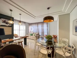 Sala de estar com mesa de jantar e luminárias pendentes.