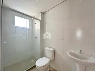 Banheiro com box de vidro e pia em cerâmica branca.
