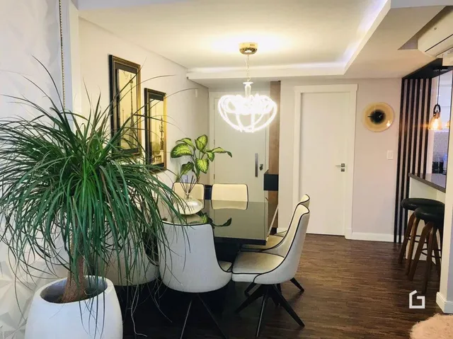 Corredor interno com piso de madeira e plantas decorativas.