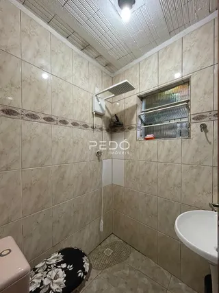 Foto de um banheiro com paredes de azulejo claro.