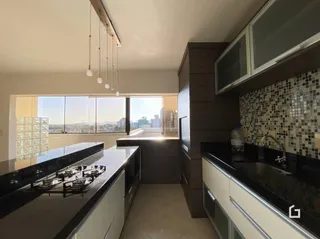 Vista da cozinha com bancadas escuras e armários em madeira.