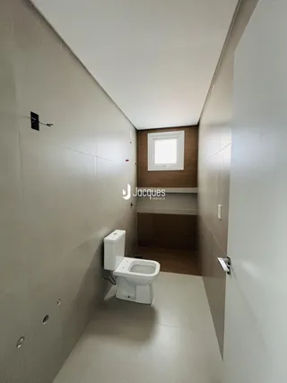 Corredor estreito com vaso sanitário em uma residência.