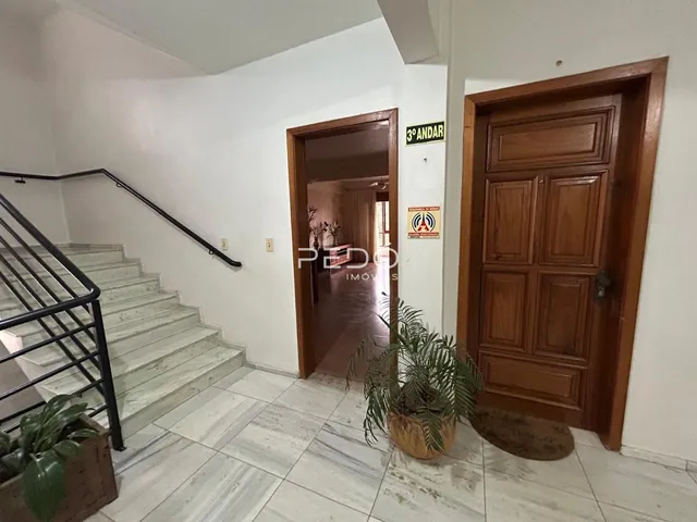 Hall de entrada com escadaria e porta de madeira em uma residência.