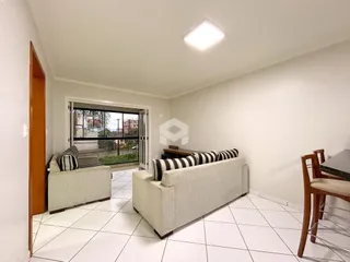 Sala de estar com piso de cerâmica e sofás brancos.