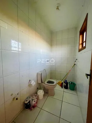 Foto interna de um banheiro com azulejos brancos e vaso sanitário.
