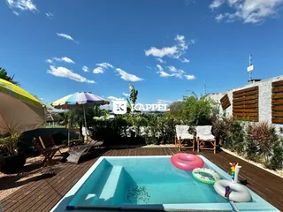 Foto de uma piscina externa com deck de madeira e área verde em um imóvel.