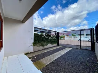 Vista da fachada de uma residência com portão de ferro e jardim.