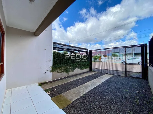 Vista da fachada de uma residência com portão de ferro e jardim.