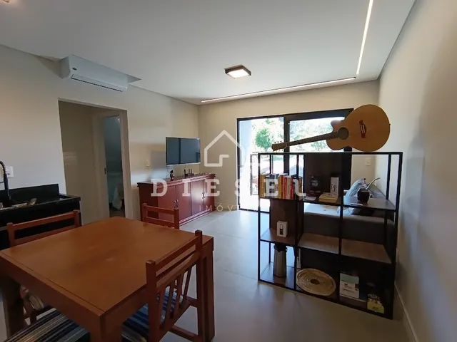 Vista da sala de jantar com mesa de madeira e armário na residência.