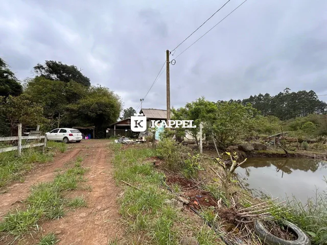 Uma vista externa mostrando uma estrada de terra e vegetação ao lado de um corpo d'água.