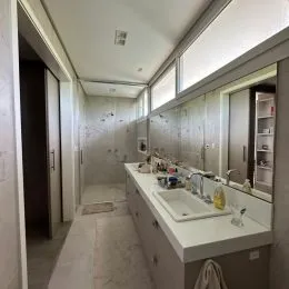 Corredor interno com paredes claras e espelhos em um imóvel.